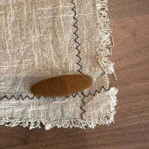 Close-up of a retro brown flocked oval hair clip on a textured linen background mat