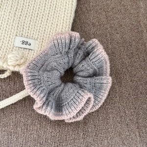 Détail du chouchou en maille gris et rose montrant la texture douce du fil et l'élastique
