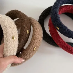 Detailed view of plush lamb wool headbands with gold logo emblem in various winter colors