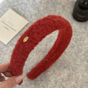 Detail view of red faux shearling headband with an elegant gold metal accent piece
