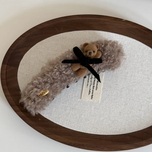 Fermaglio a banana con orsetto di peluche marrone e fiocco di velluto su vassoio