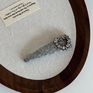 Vintage plush grey hair clip with sparkling rhinestone heart on a wooden tray