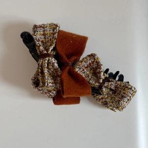 Close-up of a tweed bow hair clip with multi-layered wool fabric in a retro autumn style