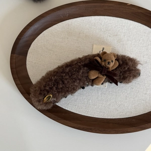 Dettaglio del fermaglio per capelli con orsetto di peluche e fiocco di velluto