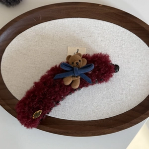 Dettaglio della clip a banana in peluche bordeaux con orsetto e fiocco blu