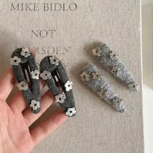 Chic grey wool floral hair clips with silver metallic flower accents in hands
