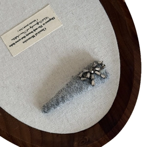 Elegant grey plush hair clip featuring a sparkling rhinestone bow on a textured knit base