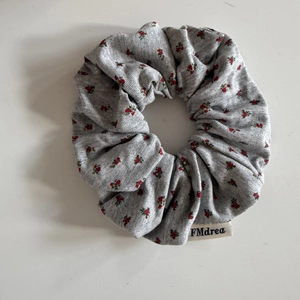 Chouchou en tricot à fleurs grises avec motifs rouges et étiquette de marque minimaliste