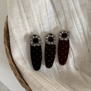 Primo piano di fermagli in velluto a pois con zirconi in nero, marrone e bordeaux.