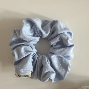 Détail du chouchou bleu clair à pois avec une petite étiquette de marque tissée