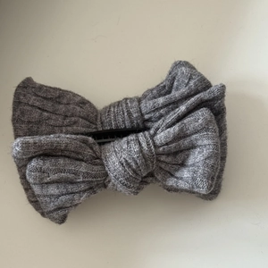 Gros plan d'une pince à cheveux à nœud en tricot gris avec texture de maille détaillée