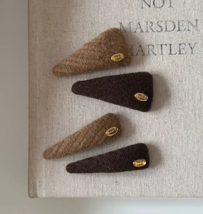 Detailed macro of vintage brown knit hair clips with golden handmade metal labels