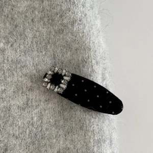 Dettaglio del fermaglio in velluto a pois neri con fibbia in zircone scintillante