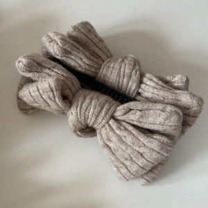 Détail du nœud papillon en tricot avec motif torsadé beige et pince banane pour cheveux