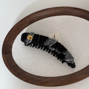 Detail of banana clip with grey plaid wool fabric and gold engraved believe medal
