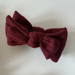 Détail du nœud à cheveux en tricot bordeaux avec motif torsadé et pince noire