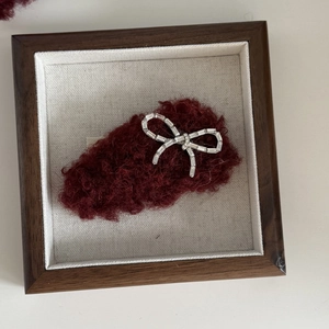 Sparkling rhinestone bow hair clip on burgundy velvet background in a wooden frame