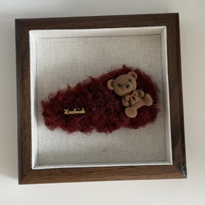 Detail of burgundy plush hair clip featuring a small flocked bear and a gold handmade tag