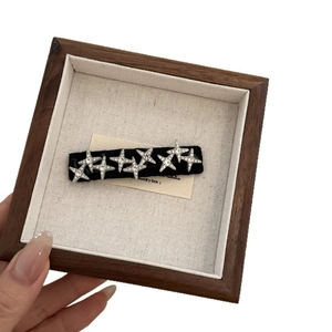Barrette en tissu noir avec huit étoiles étincelantes en strass sur support d'exposition