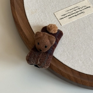 Cute brown plush bear hair clip with plaid pattern on a wooden tray for women