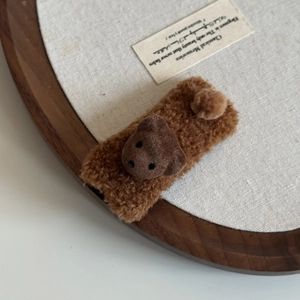 Close-up of brown plush bear hair clip featuring soft fleece texture and cute bear head