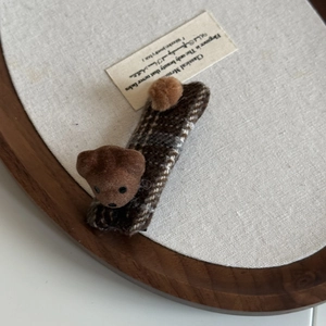 Vintage checkered teddy bear hair clip with brown flocking and plush ball on wooden tray
