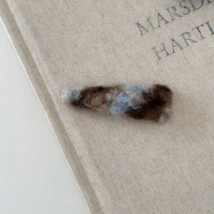 Gros plan sur la barrette à cheveux en polaire colorée au design camouflage sur lin