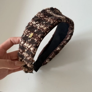 Close-up of vintage brown tweed headband featuring woven fabric and gold metal Love charm