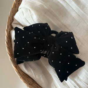 Detail of black velvet bow hair claw clip with sparkling rhinestones on fabric background