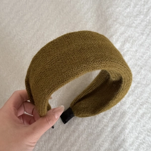 Close-up of thick knitted mustard green headband with ribbed texture for autumn winter