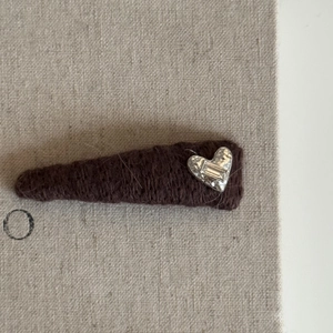 Brown knitted hair clip with silver heart charm and zircon stone on beige linen