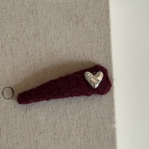 Close-up of burgundy felt triangular hair clip with silver heart and zircon inlay