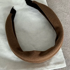 Detail van een dikke bruine fluwelen haarband met vulling op een wit stoffen zakje
