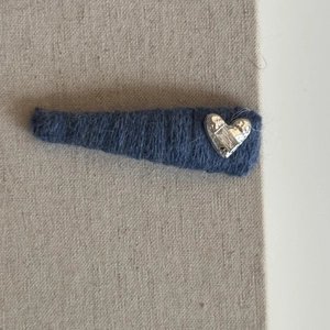 Detail of blue knit hair clip with textured silver heart metal ornament and fabric wrap