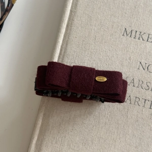 Elegante molletta a fiocco in feltro bordeaux con targhetta dorata su copertina di libro