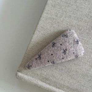 Detail of pink wool felt drop-shaped BB hair clip with black bow and polka dots