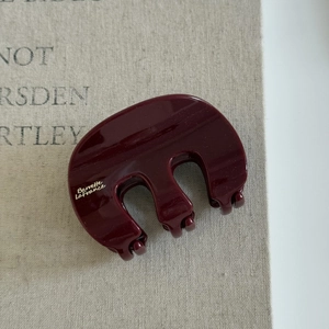 Gros plan d'une pince à cheveux rouge bordeaux en résine avec finition brillante