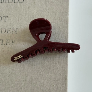 Gros plan d'une pince à cheveux bordeaux avec inscription Barrette La France dorée et brillante