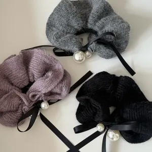 Detail view of plush knitted hair scrunchies with ribbons and elegant pearls in three colors