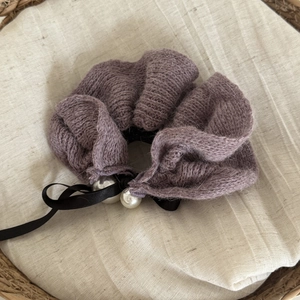 Close-up of purple knitted scrunchie with a black silk bow and elegant white pearls