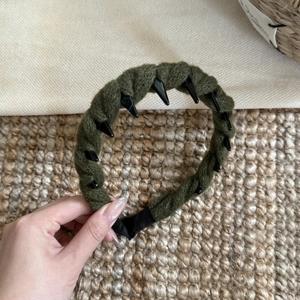 Détail du serre-tête tressé vert foncé avec pointes punk noires et texture en laine
