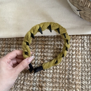 Gros plan sur le bandeau en tricot torsadé jaune moutarde avec détails de clous coniques