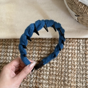 Détail d'un serre-tête en tricot bleu marine avec pointes noires de style punk