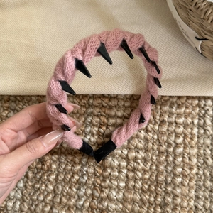 Texture détaillée du serre-tête en tricot rose avec des pointes décoratives noires punk