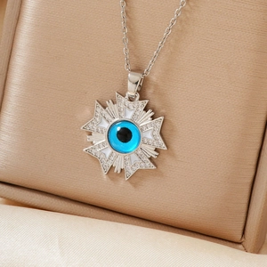 Detail of evil eye starburst pendant with blue bead, white enamel, and sparkling crystals