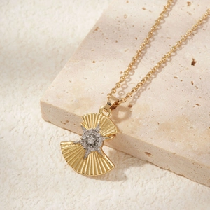 Golden fan-shaped necklace with star-shaped zircon pendant on natural stone display