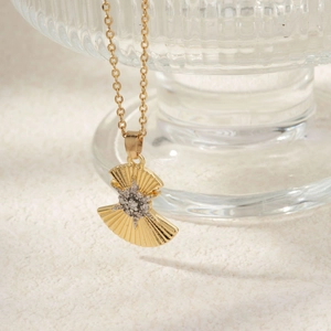 Macro shot of fan-shaped golden necklace pendant with zircon star and textured finish