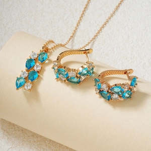 Makroaufnahme von Goldschmuck-Set mit tropfenblauen und runden weißen Zirkonia