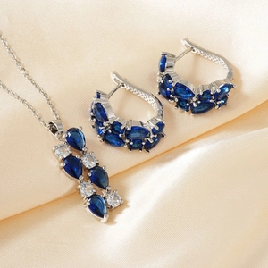 Detail eines Schmucksets mit birnenförmigen blauen Zirkonia auf champagnerfarbenem Satin