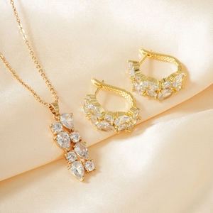 Detail von goldenem Schmuckset mit Zirkonia im Birnenschliff auf Champagner Seide